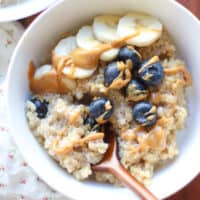 An overhead shot of quinoa porridge with blueberries, banana, and peanut butter drizzle.