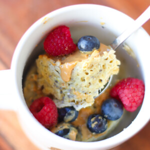 An overhead shot of scooped mug cake with peanut butter and berries.
