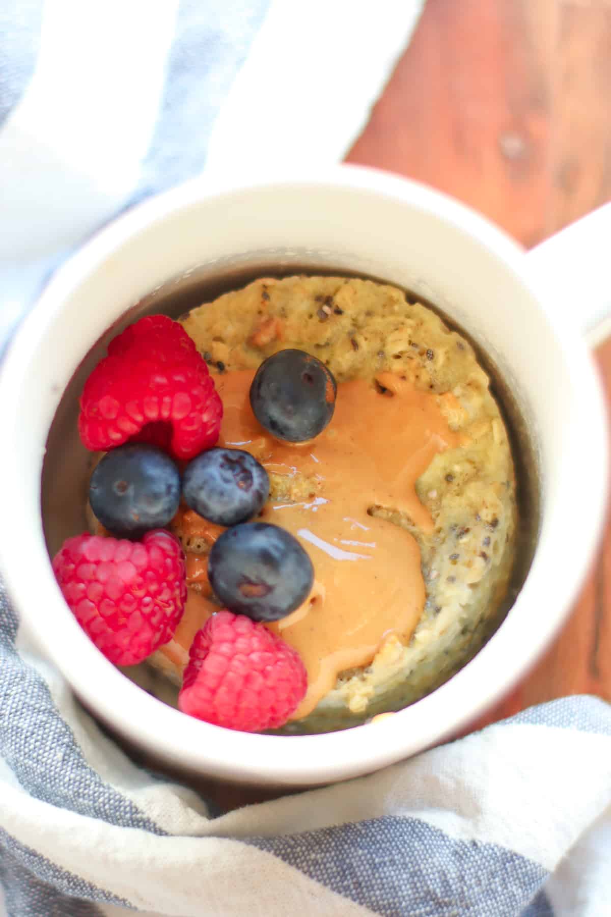 Cooked oatmeal mug cake with peanut butter and berries.