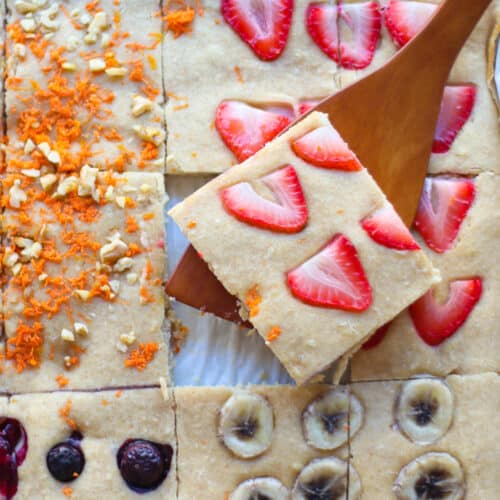 Close up of baked sheet pan pancakes with a square of strawberry topping cut out.