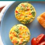Close up of two baked egg muffins on a blue plate.