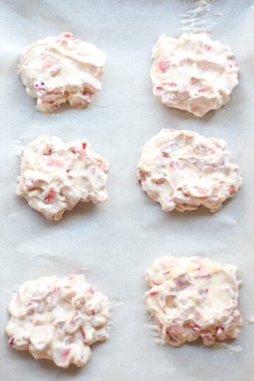Strawberry yogurt clusters laid out on parchment lined baking sheet.