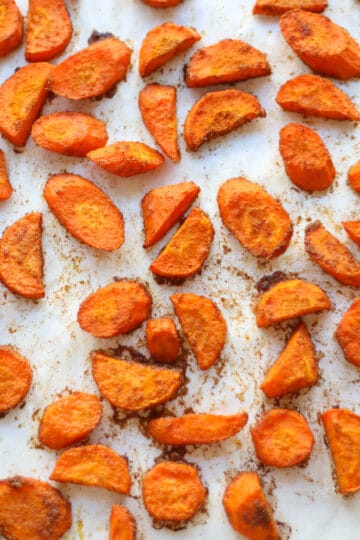 Sliced carrots on parchment after roasting.