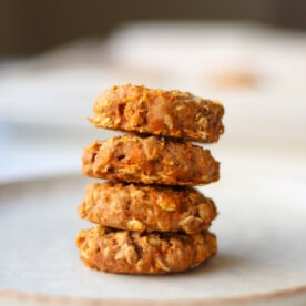 Side view of a stack of four baked cookies on a white plate.