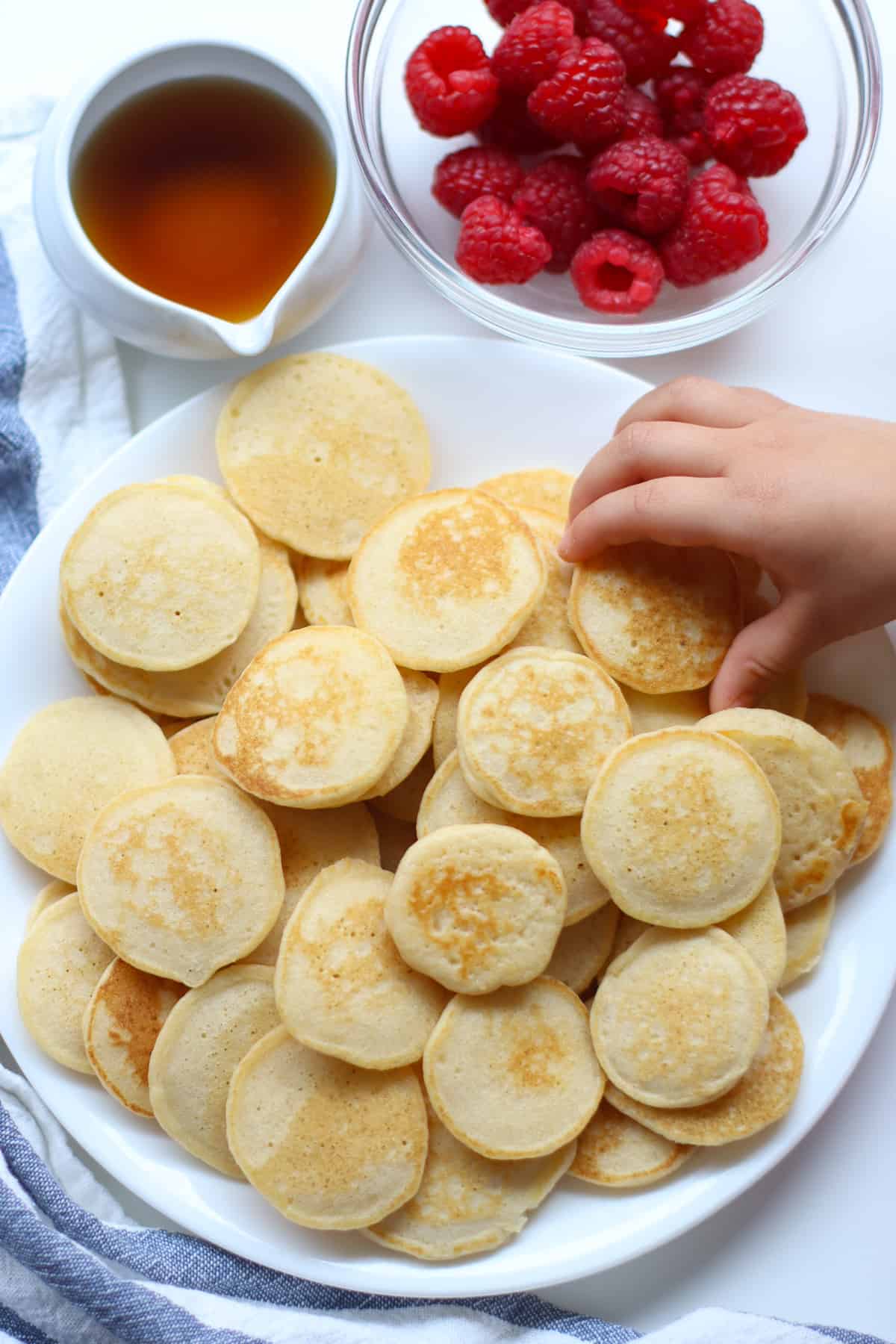 Mini pancakes piled on a white plate.
