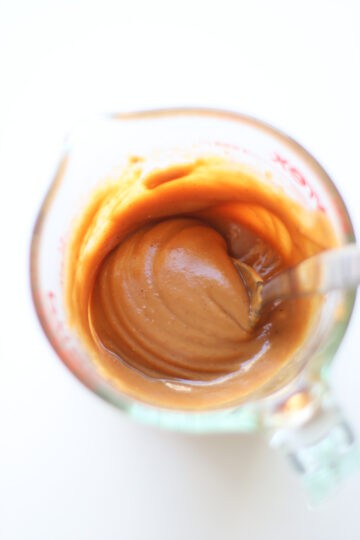 Peanut butter sauce mixed together in a glass measuring cup.