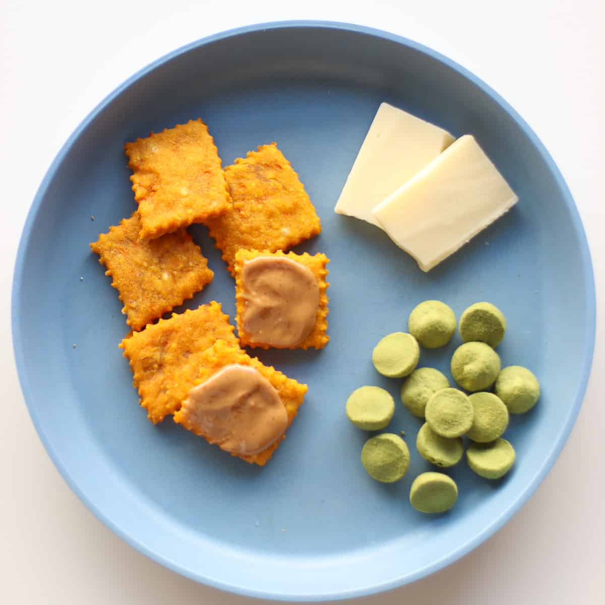 A plate for toddlers with cheese crackers and other snacks.