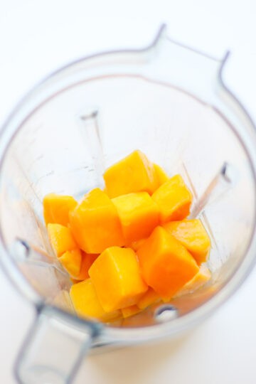 Mango cubes added to a blender.