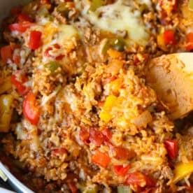 A close up of the finished unstuffed pepper dish in a white skillet with a wooden spoon.