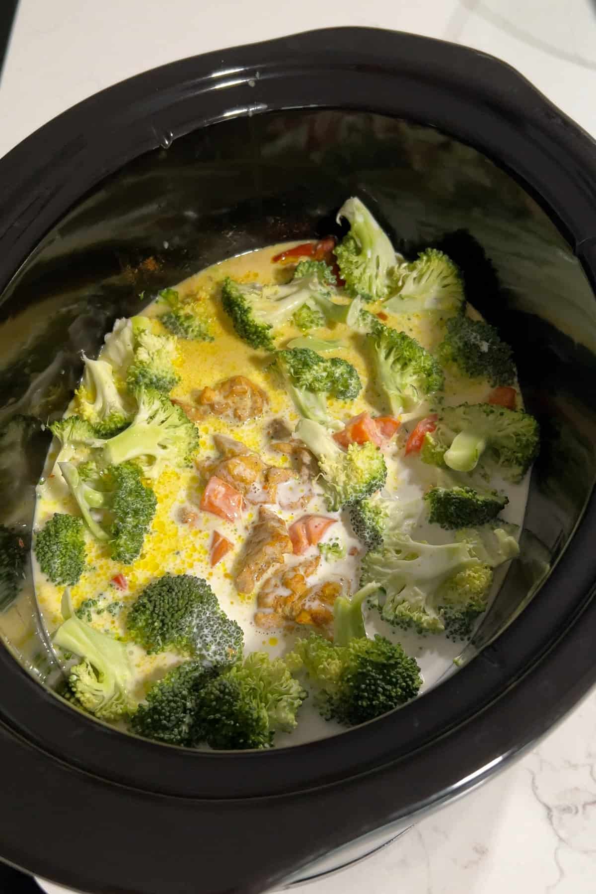 The cooked chicken curry with the broccoli and coconut milk having been added toward the end of cooking.