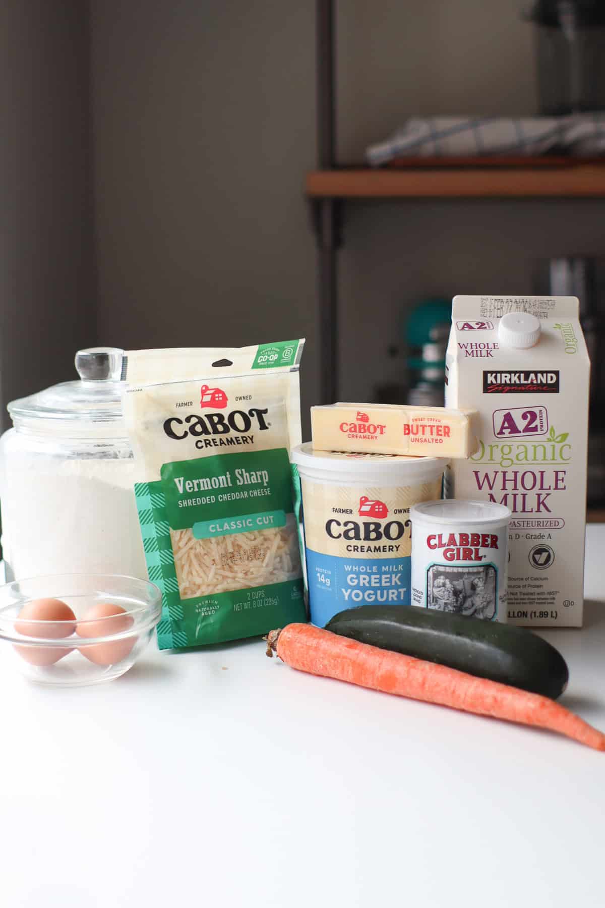 All ingredients for savory cheese pancakes sitting in their containers on a white countertop.
