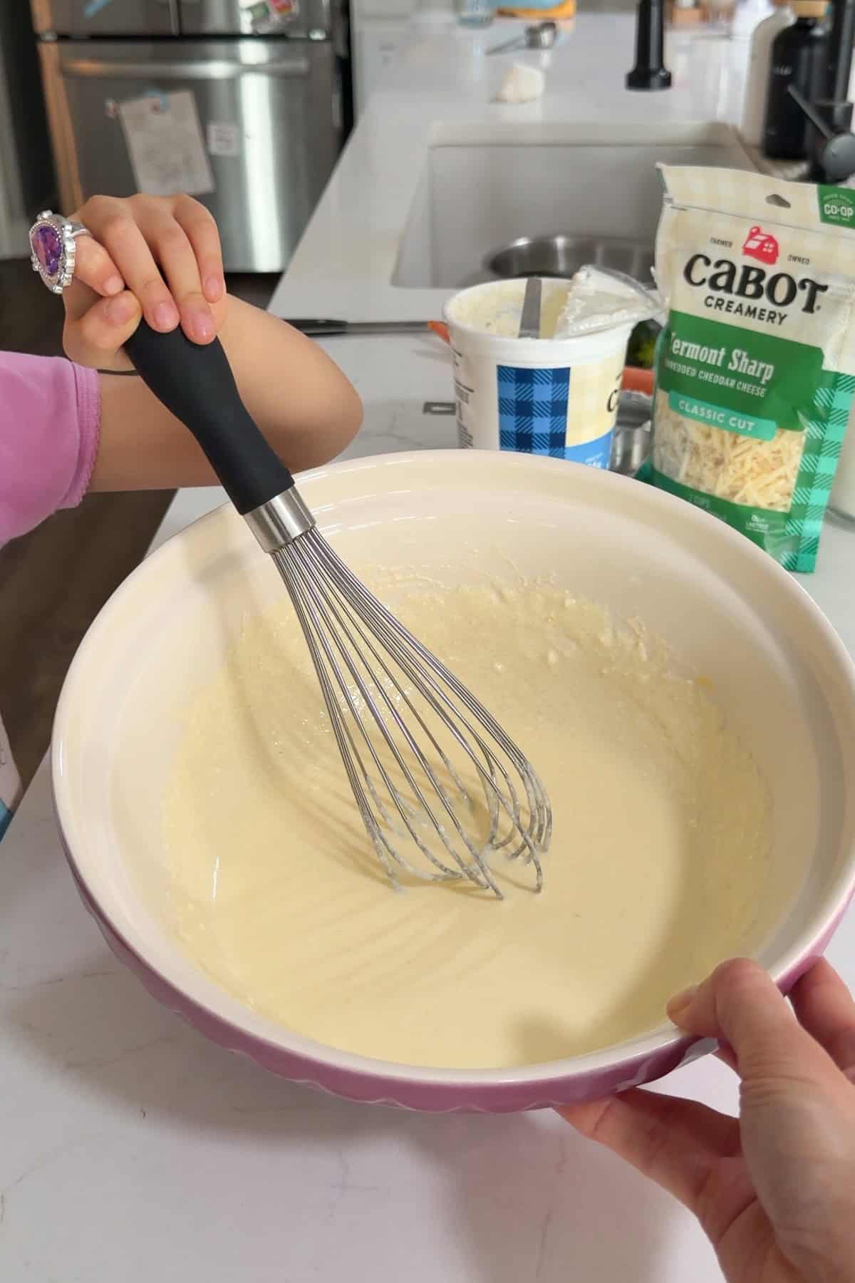 The Greek yogurt, eggs, melted butter, and the milk being whisked together until smooth.