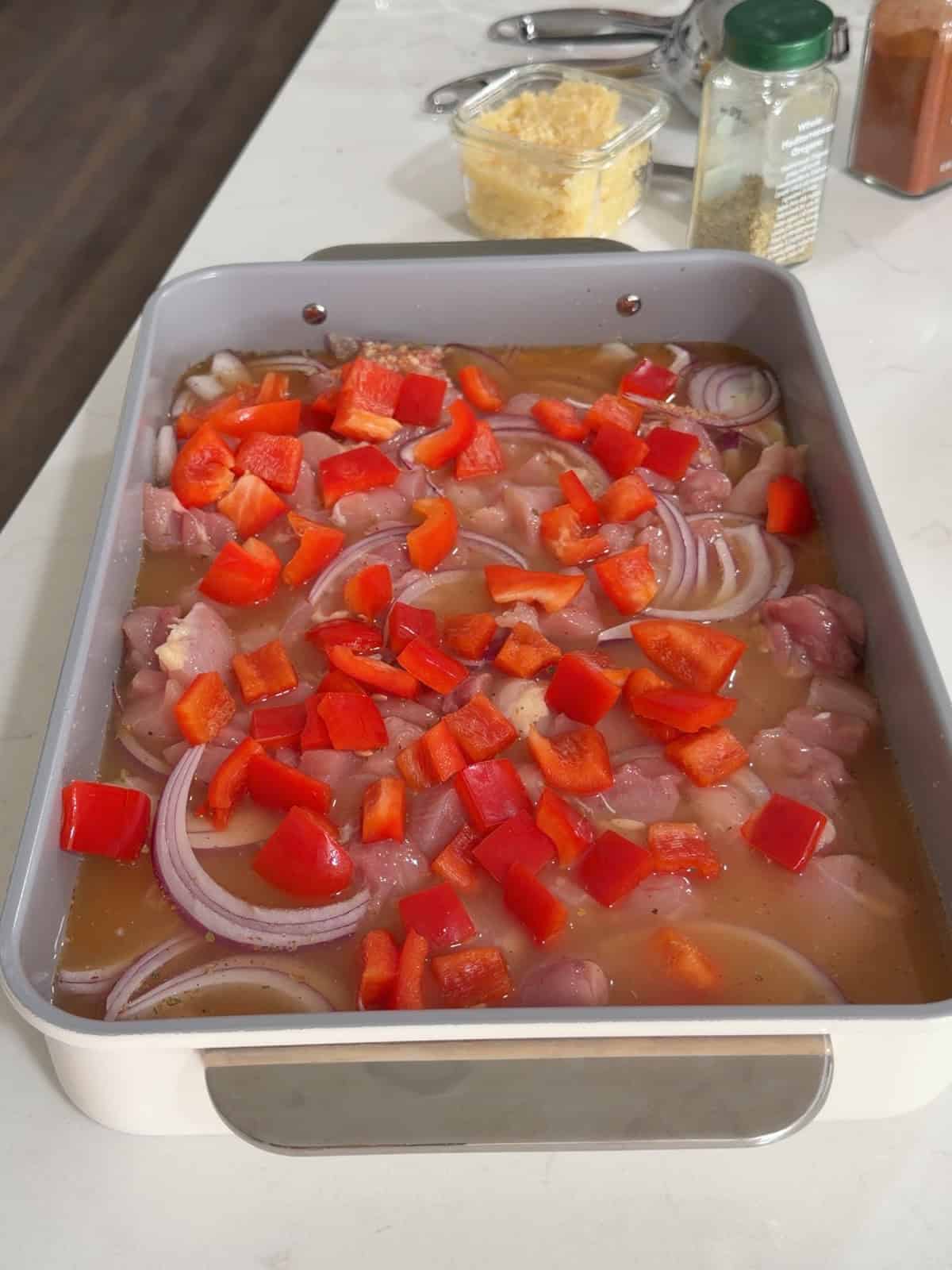 Orzo chicken onion in chicken broth with red bell peppers on top.