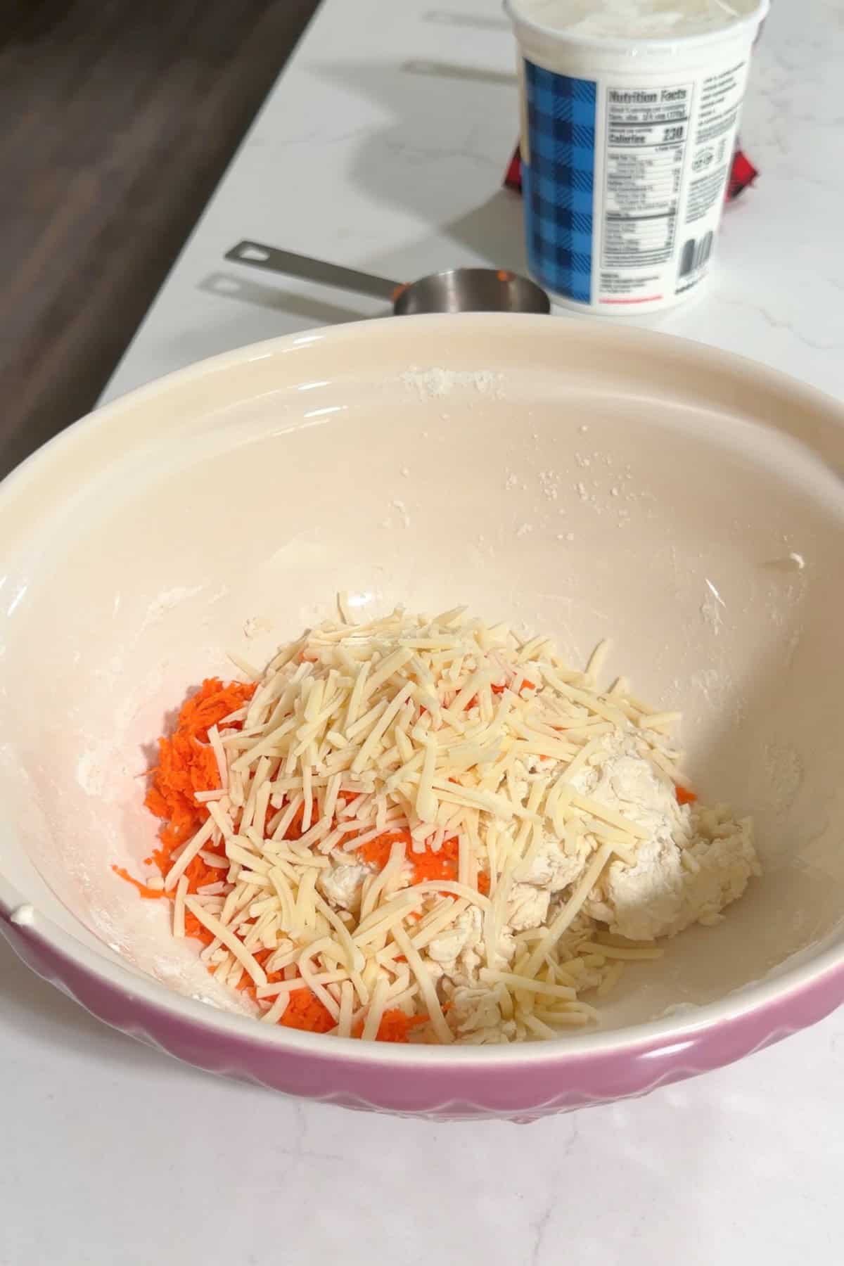 Shredded carrots and cheese added to the bowl.