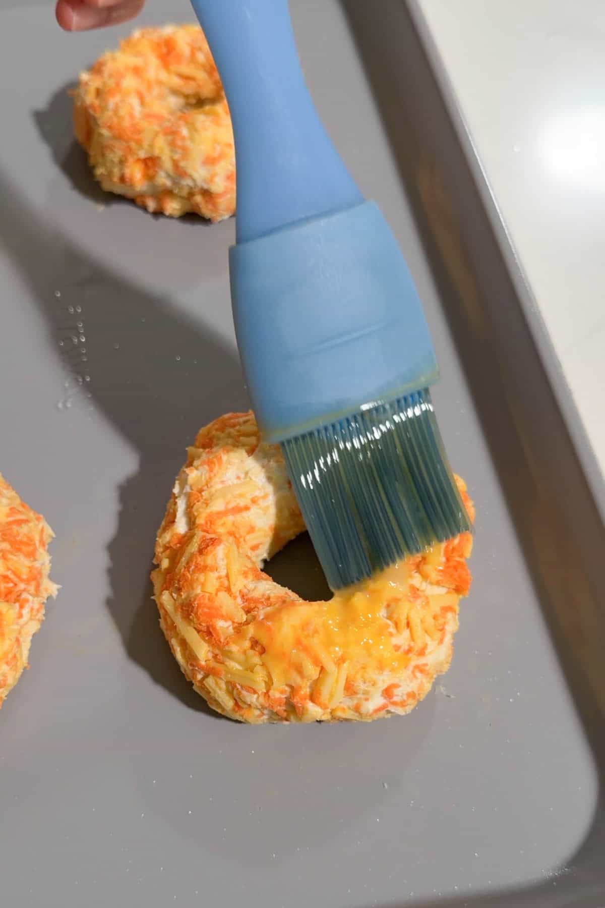 A bagel being brushed with egg wash.