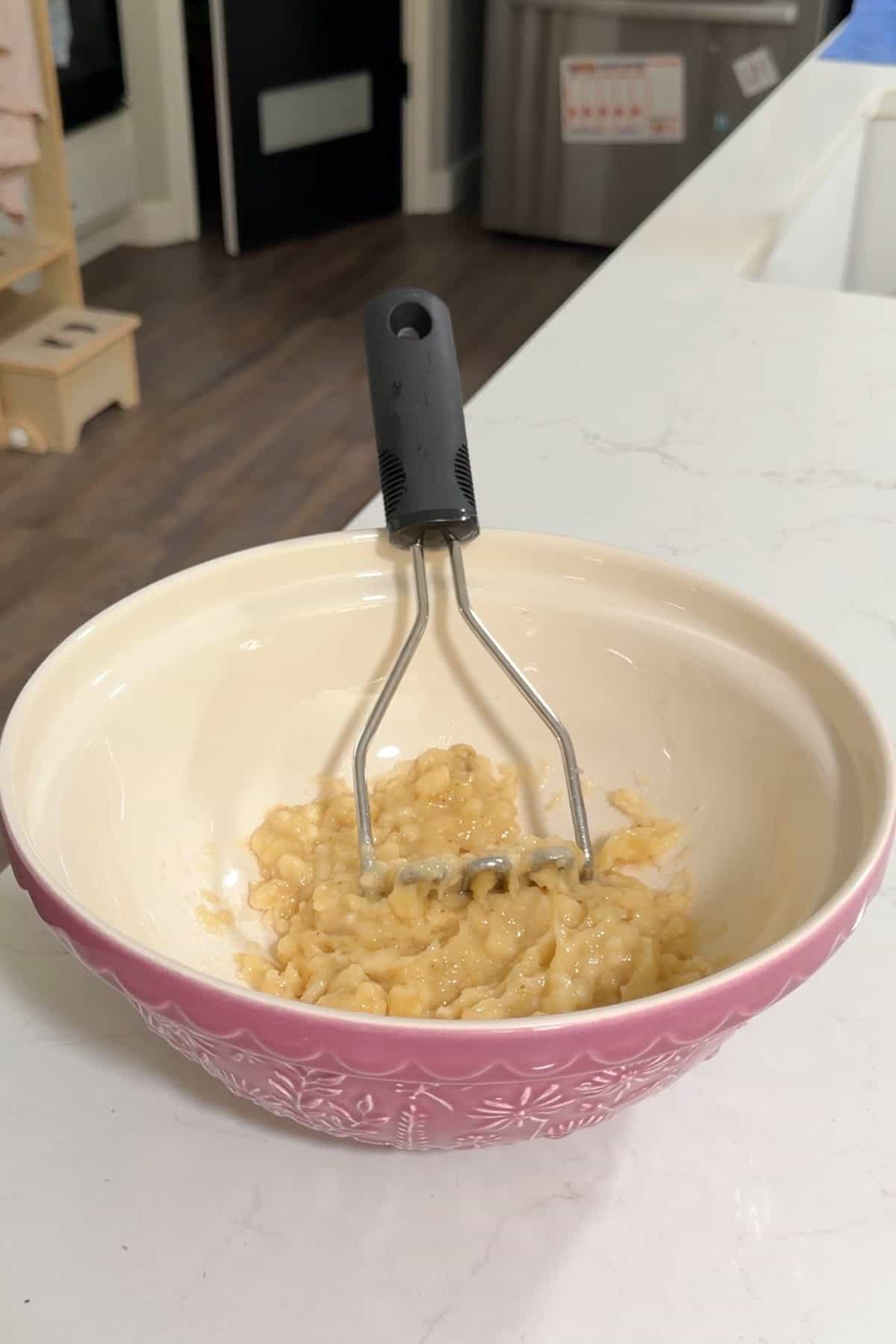 Mashed bananas in a large purple bowl.