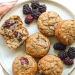Baked banana blackberry muffins on a plate with fresh blackberries.