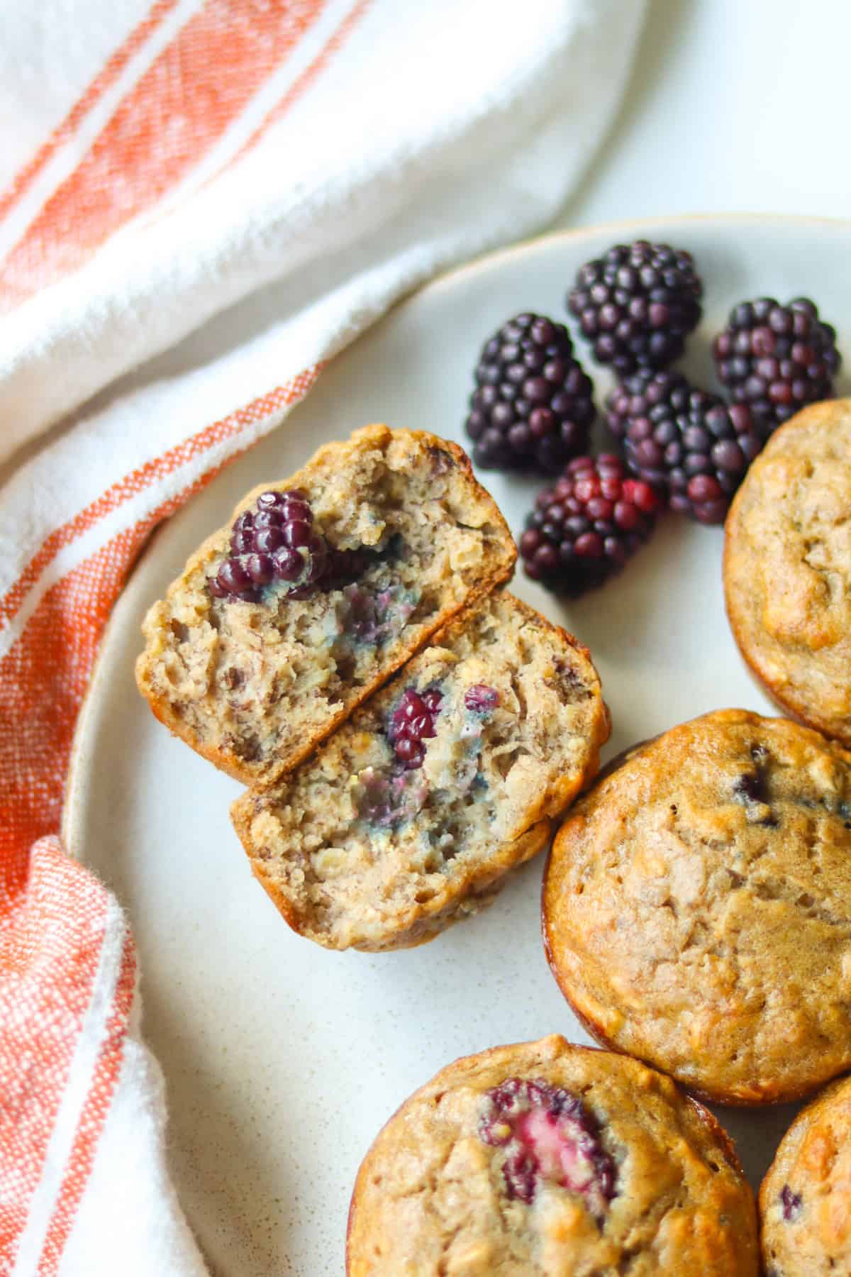 Baked banana blackberry muffins on a plate with fresh blackberries.