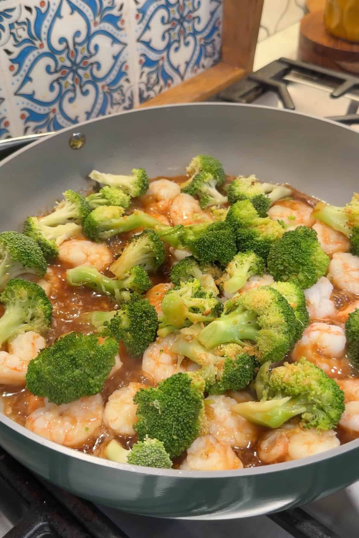 Broccoli added to the cooked shrimp and sauce.
