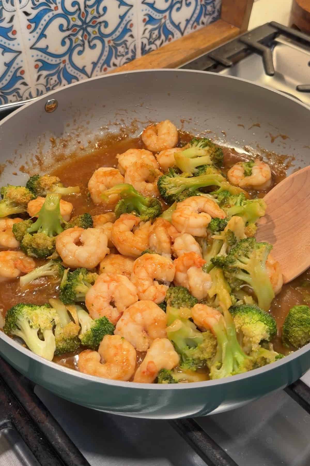 Shrimp and broccoli being tossed in a stir fry sauce.