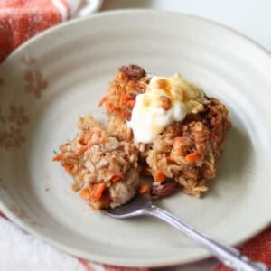 Sliced carrot cake baked oatmeal on a small plate with a fork.