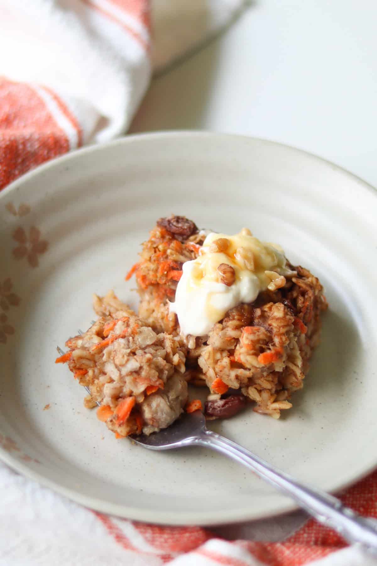 Sliced carrot cake baked oatmeal on a small plate with a fork.