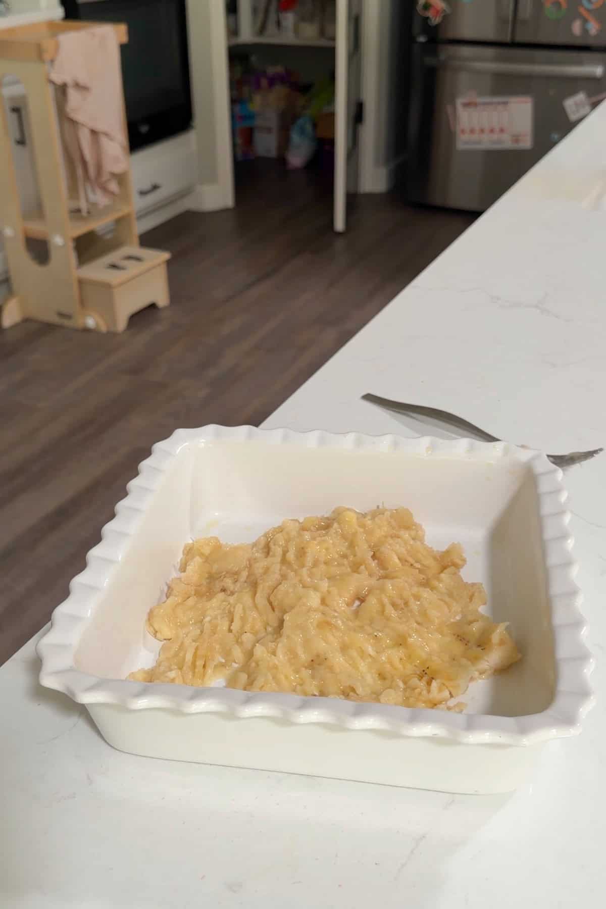 Banana mashed in a white square baking dish.
