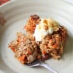 Sliced carrot cake baked oatmeal on a small plate with a fork.