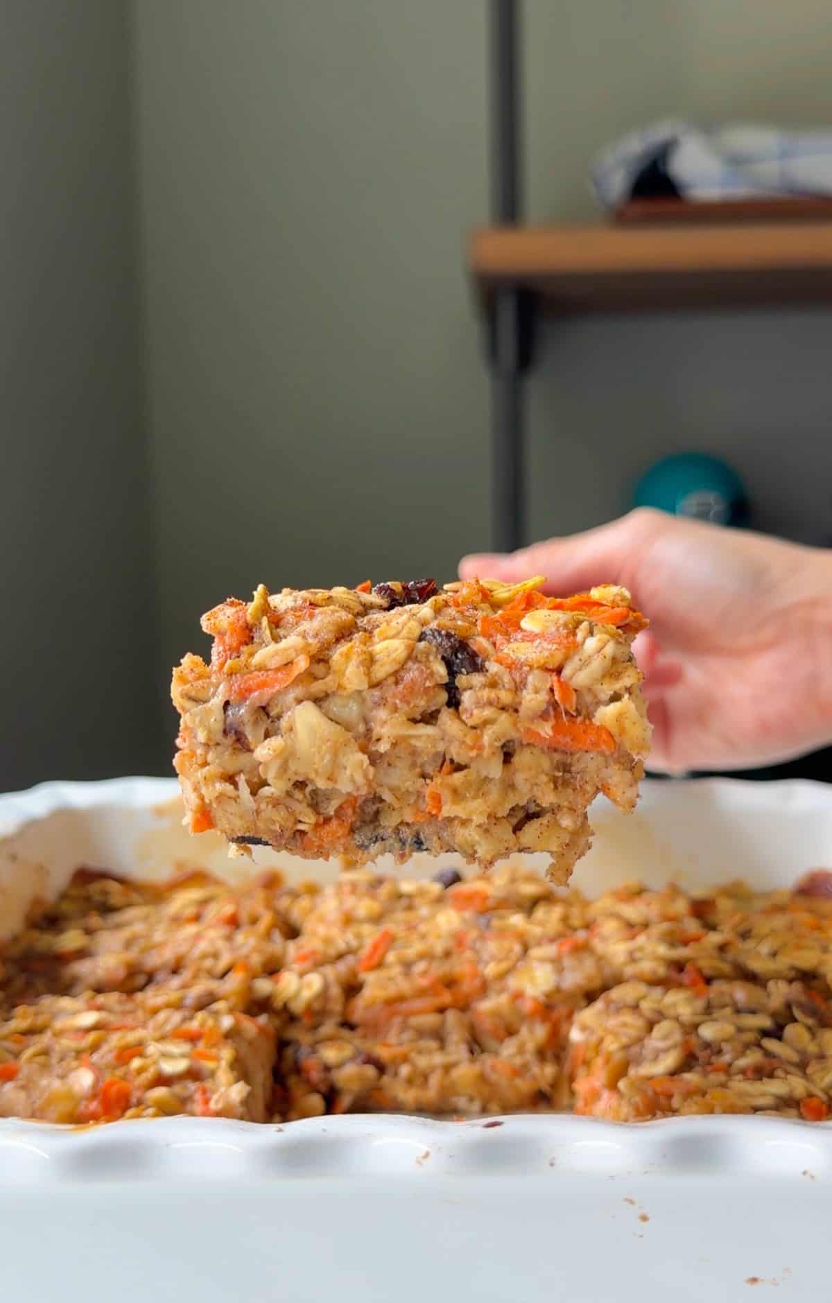 Sliced carrot cake baked oatmeal scooped with a wooden spatula.