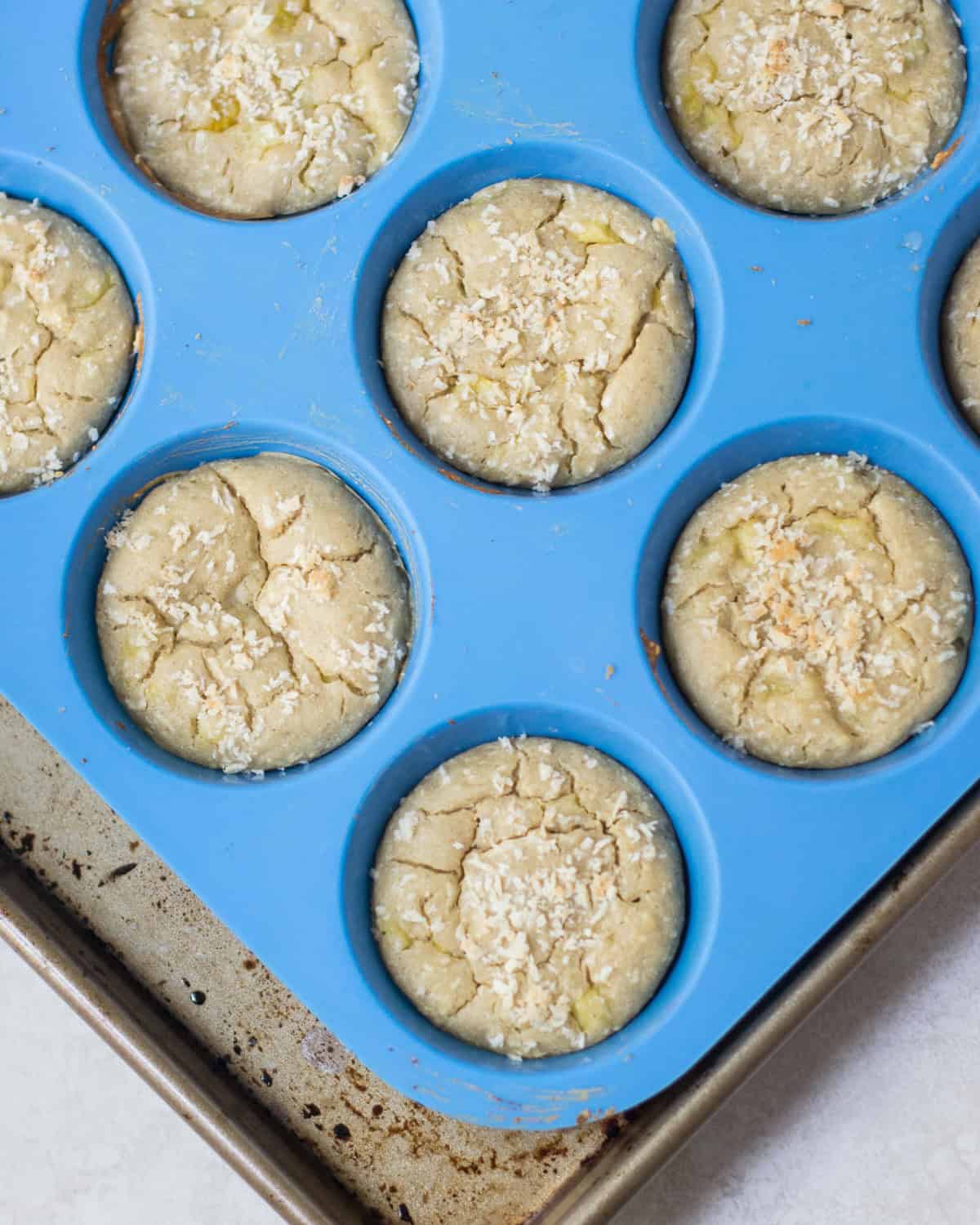 Baked pineapple coconut muffins in a blue silicone muffin pan.