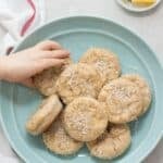 Pineapple coconut muffins placed on a blue plate with a toddler's hand grabbing one.