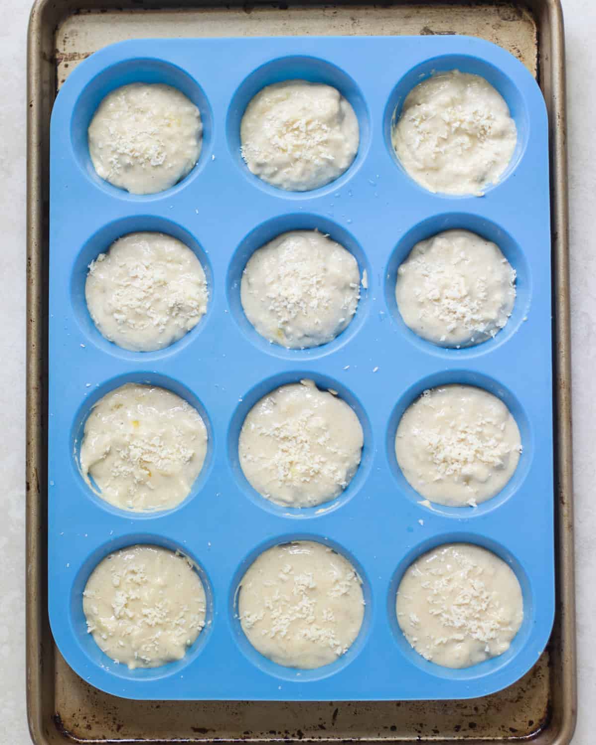 Muffin batter transferred to a blue silicone muffin pan.