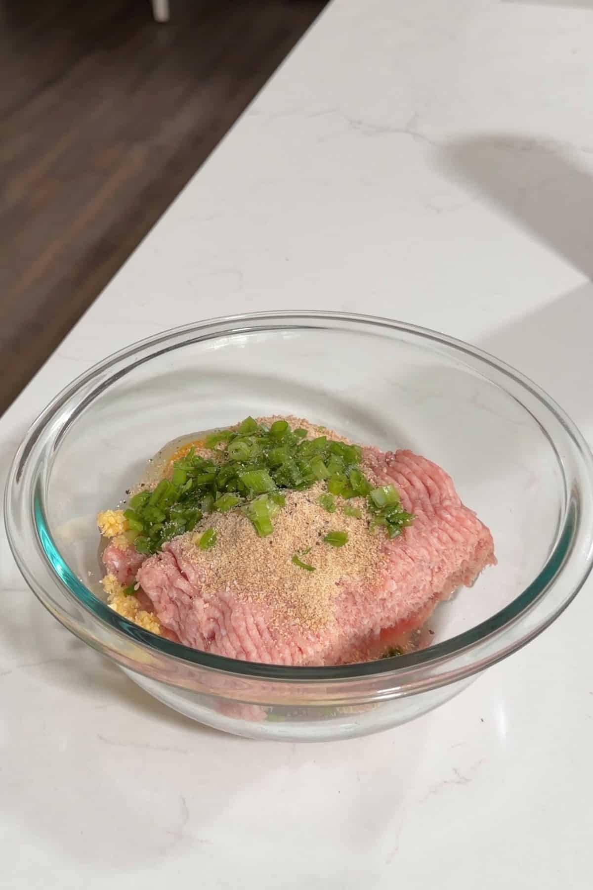 Ground turkey and the rest of the ingredients in a glass bowl.