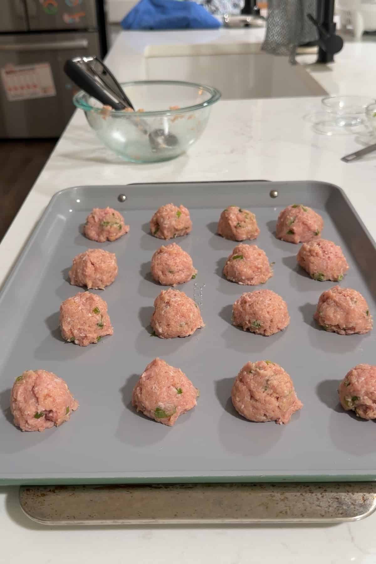 Shaped meatballs lined up on a sheet pan.