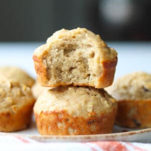 Side view of a stack of two applesauce muffins, with the top muffin having a bite taken out of it.
