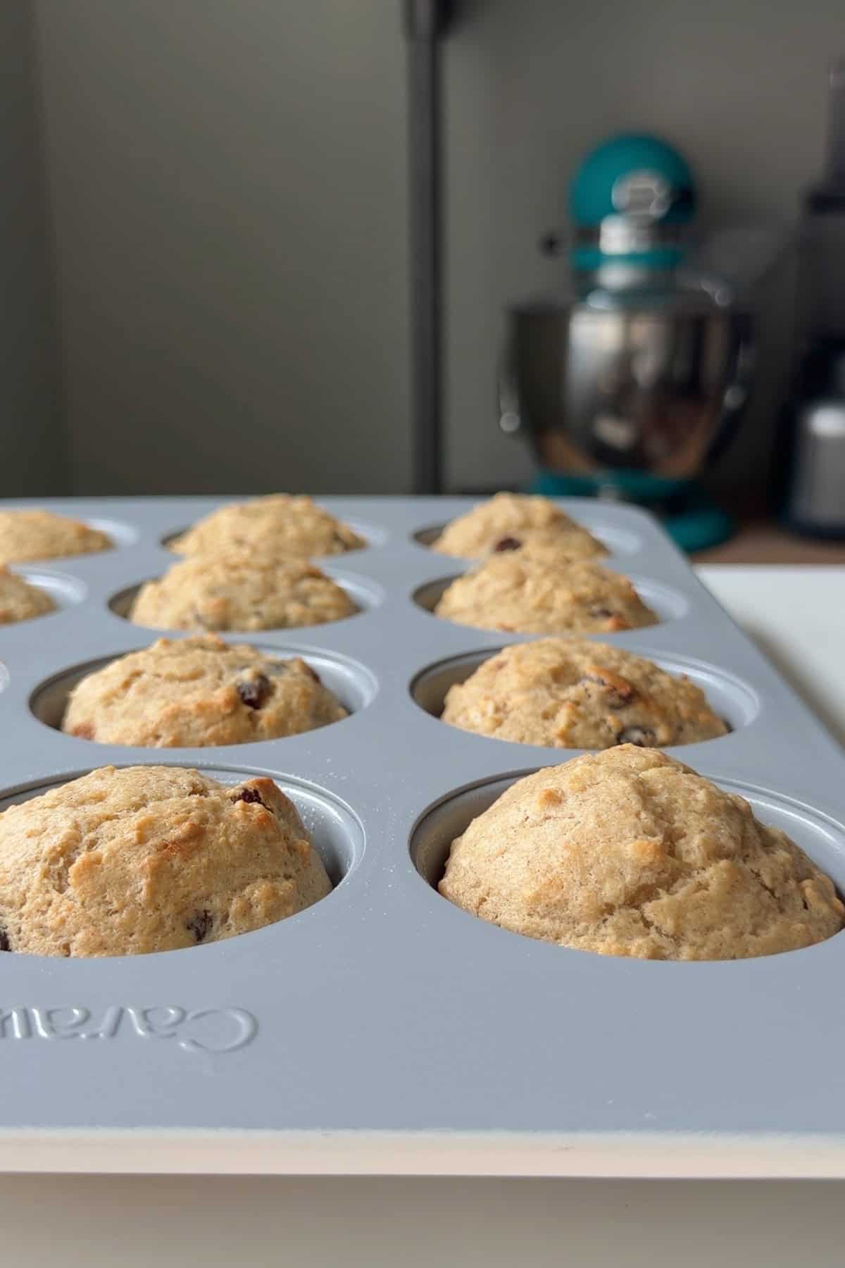 Baked muffins in a tin, lightly golden on top.