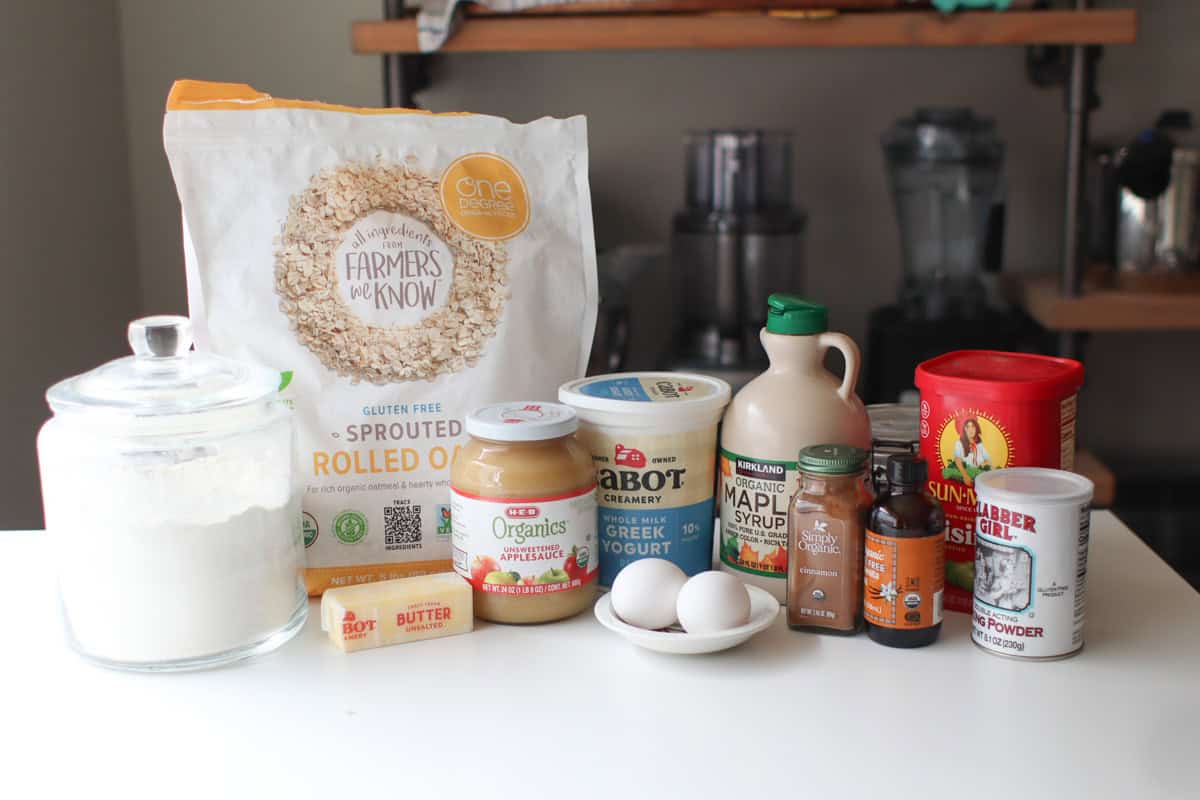 All of the ingredients for applesauce muffins sitting on a white countertop.