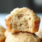 Side view of a stack of two applesauce muffins, with the top muffin having a bite taken out of it.