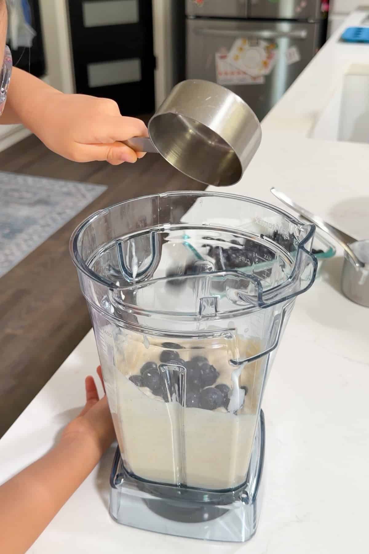 Blueberries being added to the blender.
