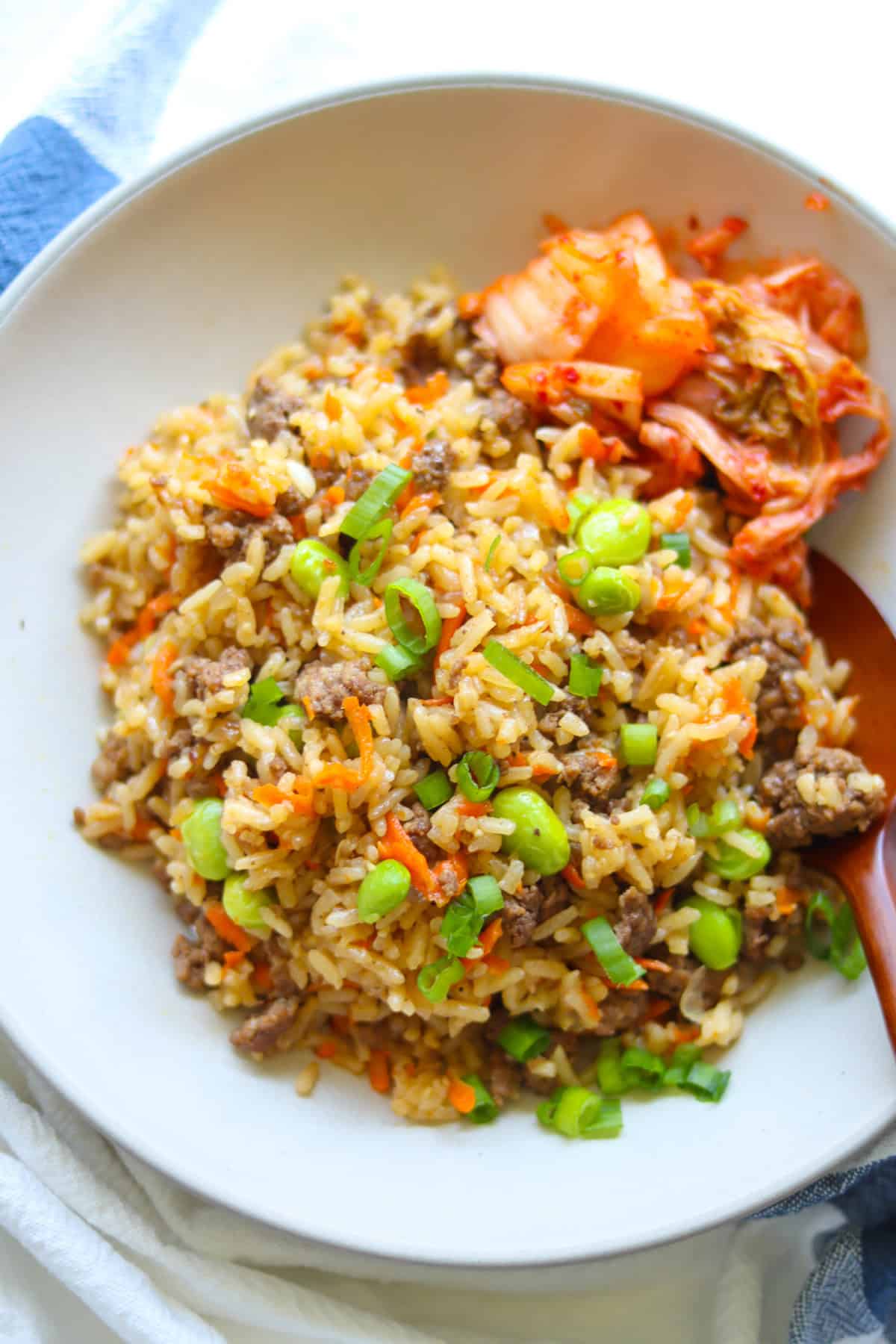 Korean ground beef and rice scooped onto a bowl with side of kimchi.