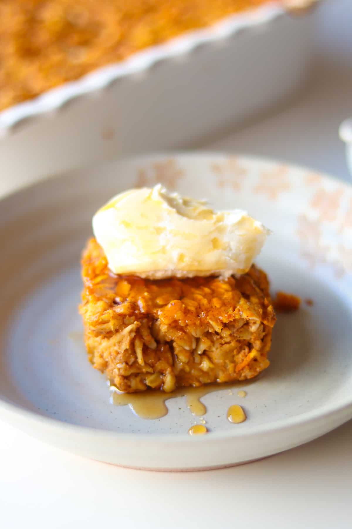 A slice of pumpkin baked oatmeal topped with mascarpone and maple syrup.
