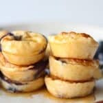 Stacked cottage cheese bites on a white plate with drizzle of maple syrup.