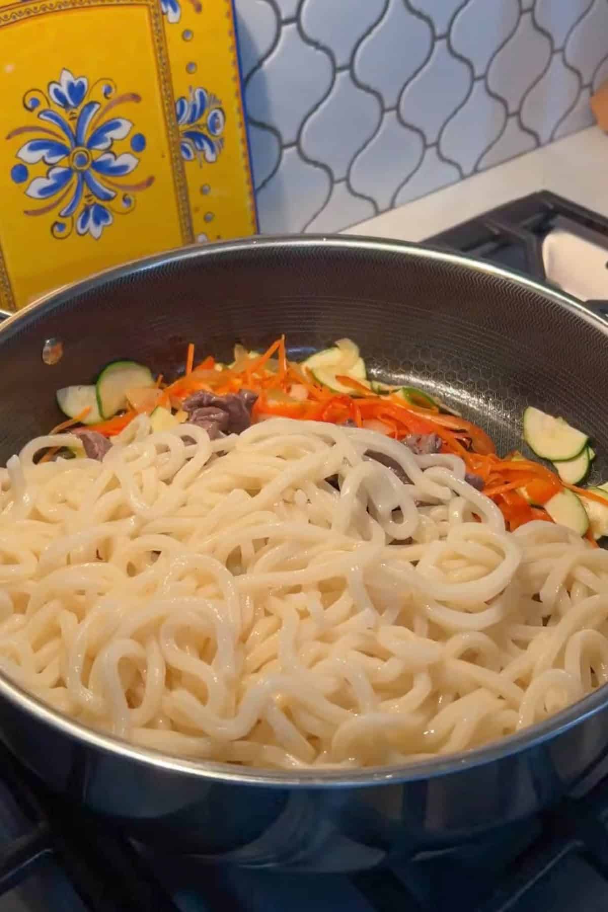 Noodles added to the cooked vegetables.