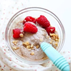 Protein chia pudding in a glass bowl with raspberries and walnuts.