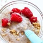 Protein chia pudding in a glass bowl with raspberries and walnuts.