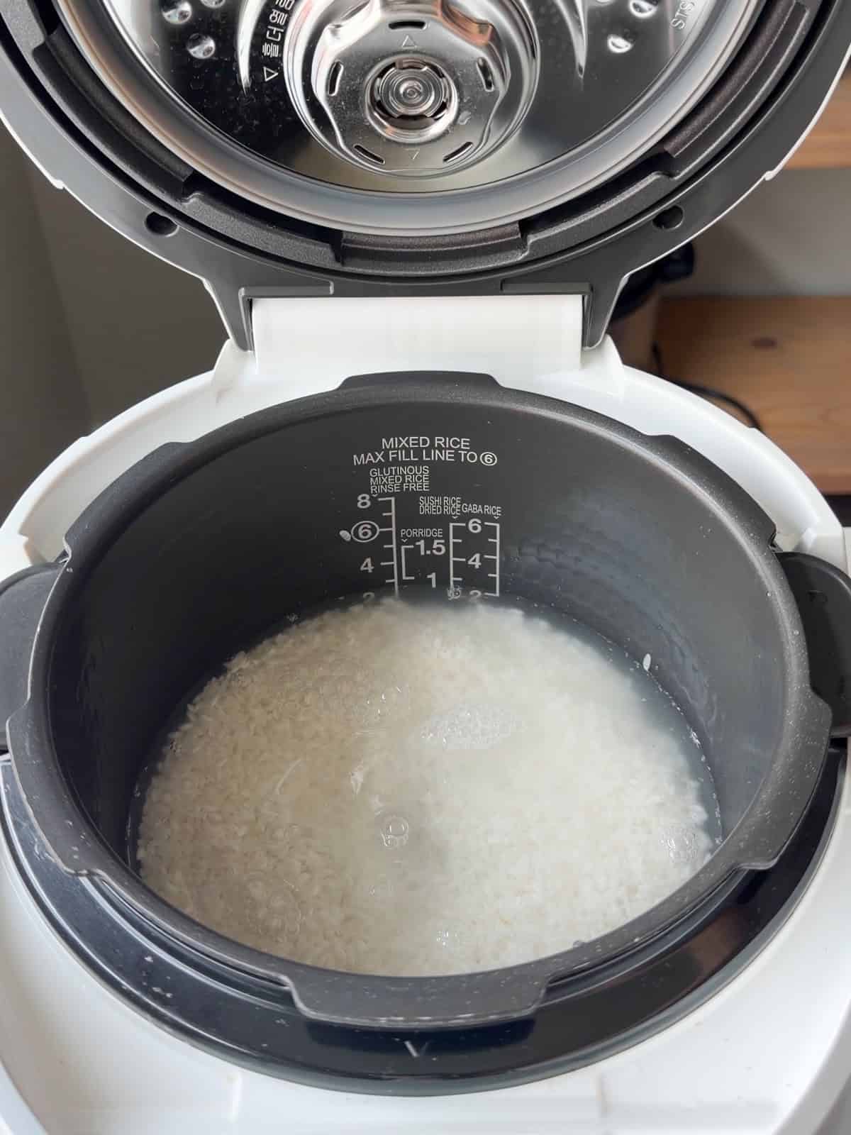 Rice submerged in water in a rice cooker.